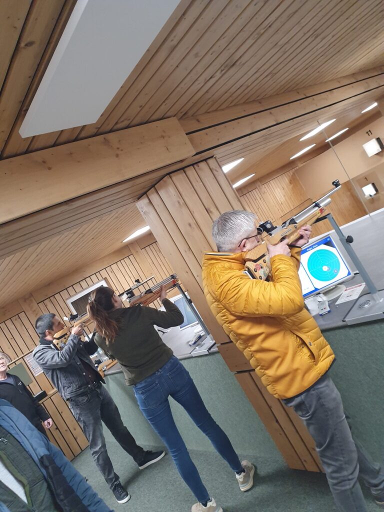 Mitarbeiter/innen an einem Indoor-Schießstand beim Luftgewehr schießen